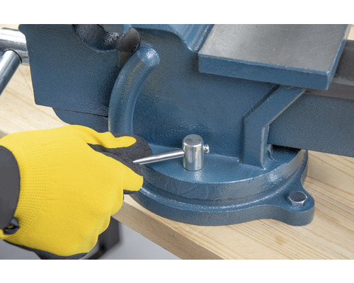 Svěrák na pracovní stůl ovládaný rukou v pracovní rukavici.