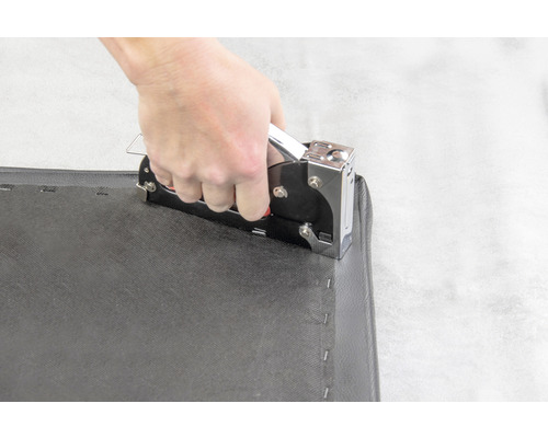 Použití ruční sponkovačky na černé tkanině