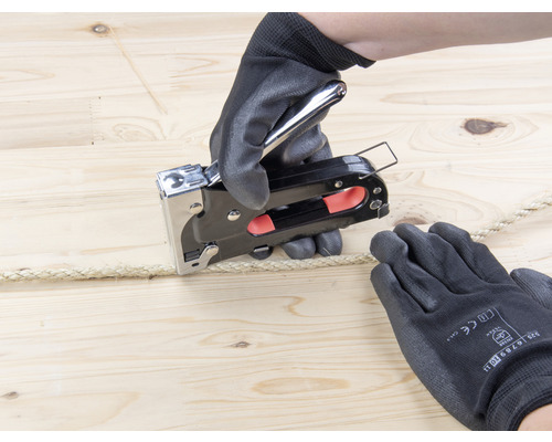 Osoba připevňuje lano k dřevu pomocí sešívačky