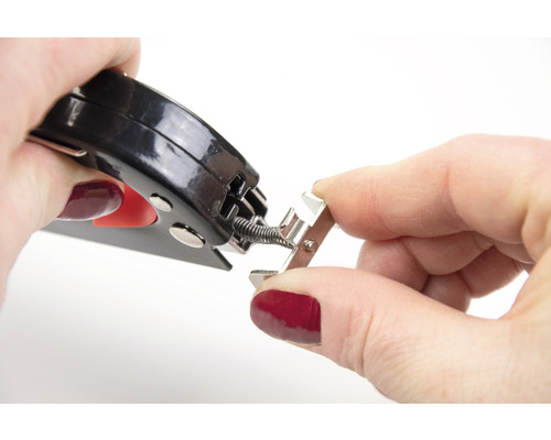 Osoba připevňuje pružinu ke kovové liště pomocí kleští.