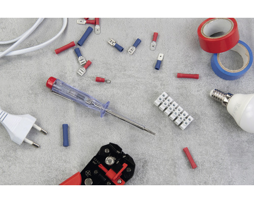 Různé elektroinstalační materiály, včetně kabelových koncovek, svorkovnice, izolační pásky, žárovky, fázové zkoušečky, odizolovací kleště a zástrčky.
