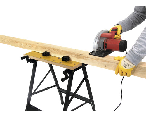 Řemeslník řeže dřevěnou desku na pracovním stole kotoučovou pilou.