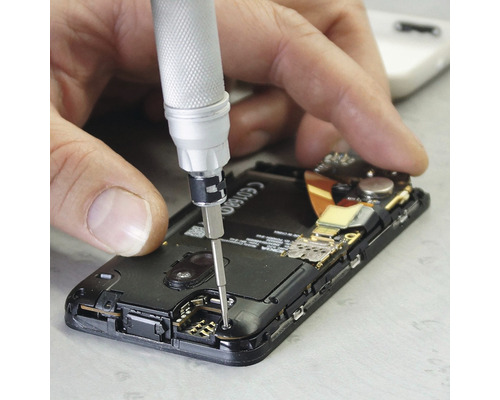 Muž opravuje smartphone pomocí šroubováku