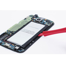 Otevřený smartphone s vyjmutou baterií a červeným nástrojem