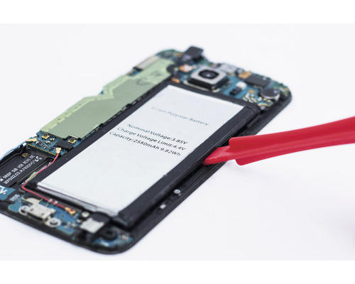 Otevřený smartphone s vyjmutou baterií a červeným nástrojem