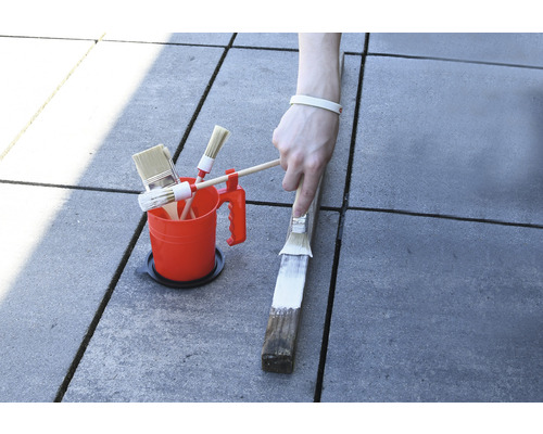 Kbelík s barvou s různými štětci a nátěr kusu dřeva