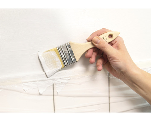 Ruka maluje stěnu štětcem o šířce 50 mm