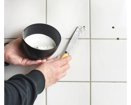 Oprava dlaždic pomocí špachtle a výplňového materiálu