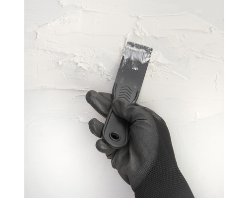 Ruka v rukavici a špachtle při omítání zdi