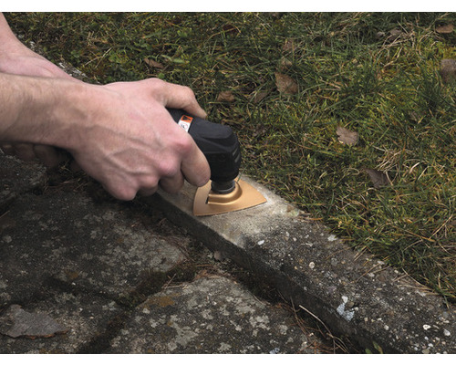 Osoba používá multifunkční nástroj na betonovém povrchu venku.