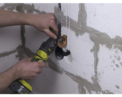 Muž pracuje na zdi s multifunkčním nástrojem pro instalatérské práce