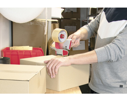 Osoba uzavírá kartonovou krabici pomocí odvíječe lepicí pásky.