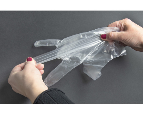 Žena si navléká průhlednou jednorázovou rukavici