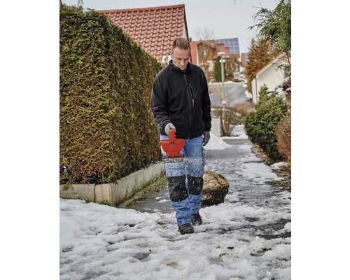 Muž odklízí sníh sněhovou frézou z chodníku