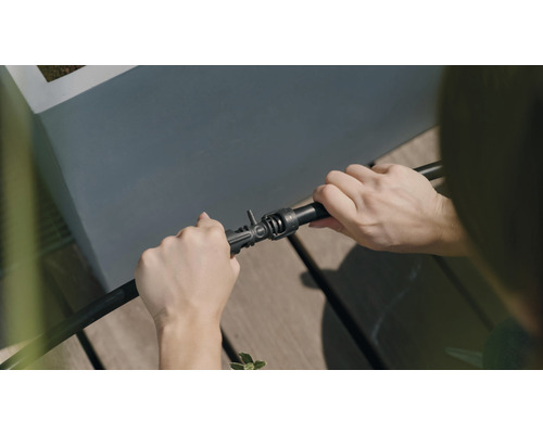 Osoba připojuje zavlažovací hadici ke konektoru.