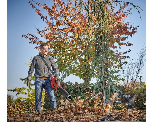 Muž používá foukač listí pro zahradnické práce.