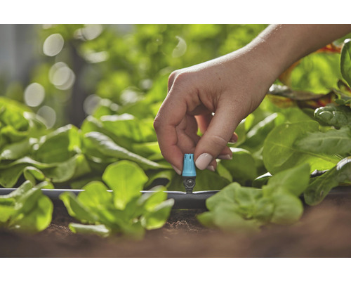 Detailní záběr ruky upravující zavlažovací systém na zahradě