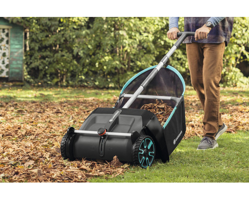 Osoba používá sběrač listí Gardena na zahradě ke sběru podzimního listí.