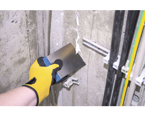 Řemeslník špachtlí stěnu špachtlí.