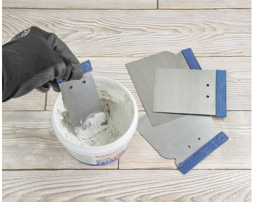 Tmel se nabírá špachtlí z kbelíku, další špachtle jsou připraveny