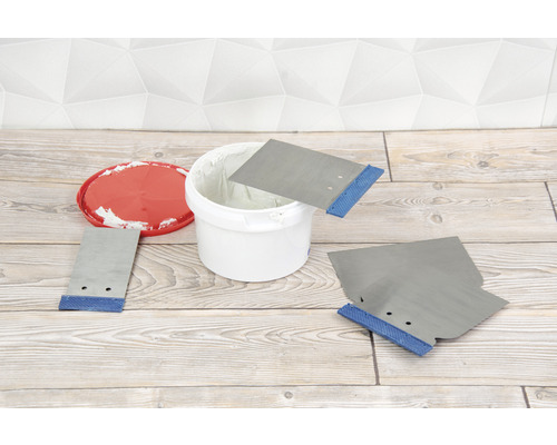 Tmel v kbelíku se špachtlemi na dřevěné podlaze