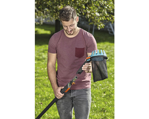 Muž připojuje sběrač ovoce k teleskopické tyči v zahradě.