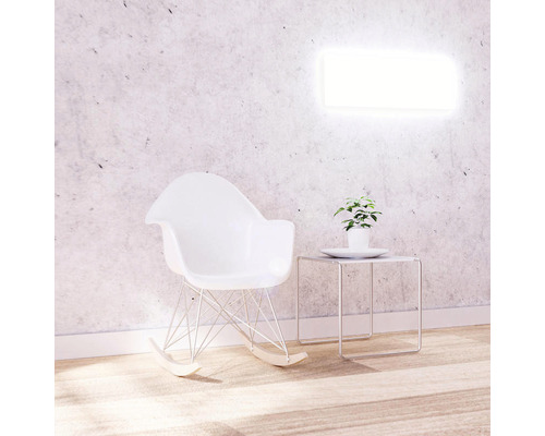 Scéna s houpacím křeslem, odkládacím stolkem a rostlinou před nástěnnou lampou