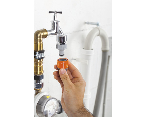 Ruka připevňuje adaptér Gardena k vodovodnímu kohoutku pro zavlažování zahrady