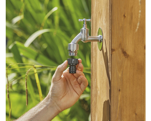 Ruka připojuje konektor kohoutku k zahradnímu kohoutku.