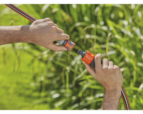 Dvě ruce spojují zahradní hadici pomocí hadicové spojky.