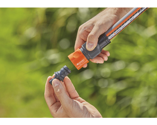 Osoba připojuje zahradní hadici k hadicové spojce