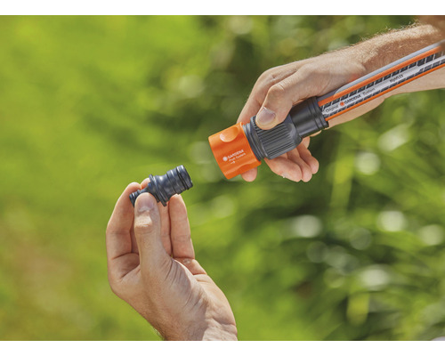 Osoba připojuje kus zahradní hadice k zahradní hadici