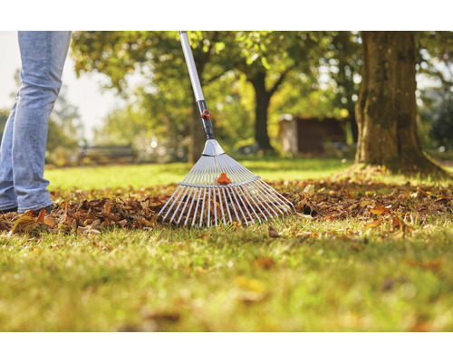 Osoba shrabává listí hráběmi na listí na zahradě.