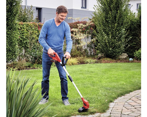 Muž používá akumulátorový vyžínač na zahradě.