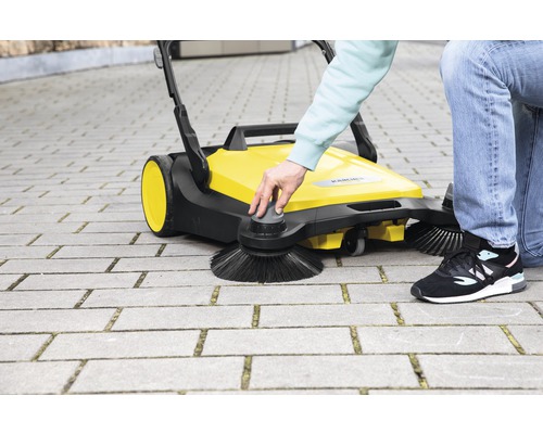 Žlutý zametací stroj Kärcher v provozu na dlažebních kostkách