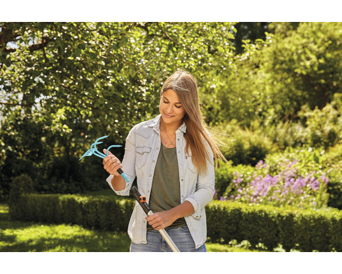 Žena drží nástavec zahradních drápů s násadou v zahradě