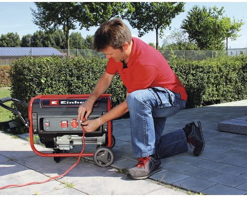 Muž připojuje kabel k elektrocentrále Einhell venku.