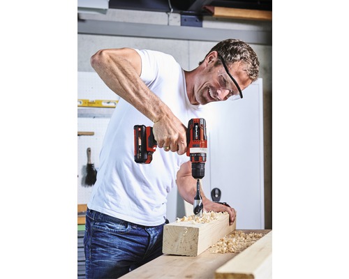 Muž vrtá akumulátorovým šroubovákem otvor do kusu dřeva.