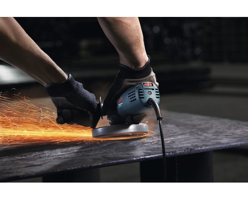 Muž opracovává kus kovu úhlovou bruskou, z čehož vznikají jiskry.