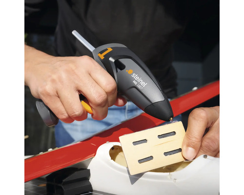 Osoba používá tavnou pistoli Steinel MG 1007 k připevnění kusu dřeva.