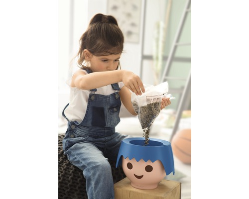 Dívka sype semena do květináče s obličejem