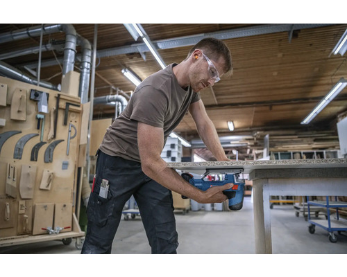 Muž řeže dřevo přímočarou pilou v dílně