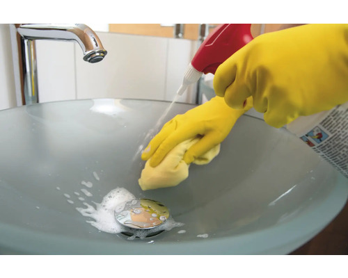 Čištění koupelnového umyvadla čisticím prostředkem a rukavicemi