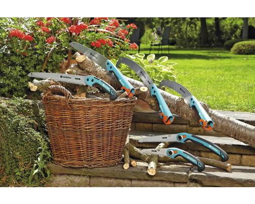 Různé ruční pily Gardena leží se dřevem v košíku