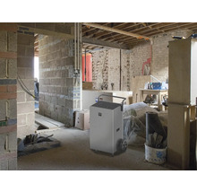 Odvlhčovač v hrubé stavbě s cihlovými stěnami a nedokončenými průchody.