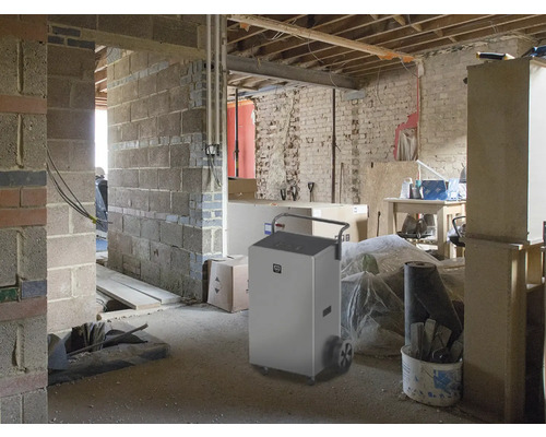 Odvlhčovač v hrubé stavbě s cihlovými stěnami a nedokončenými průchody.