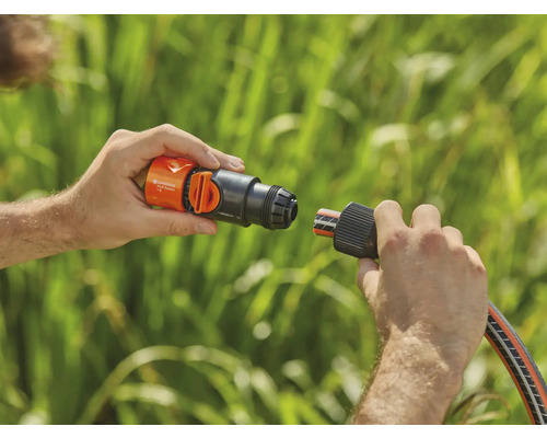 Osoba připojuje hadicový konektor Gardena k vodovodnímu kohoutku.