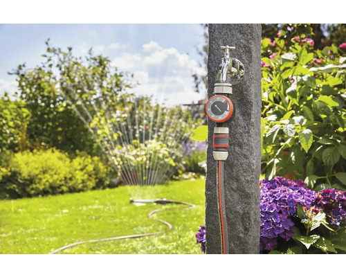 Zahradní zavlažovací systém s vodovodním kohoutkem, časovačem zavlažování a zahradní hadicí na zahradě