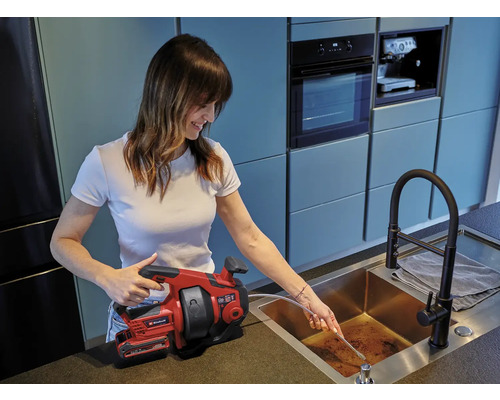 Žena používá instalatérské pero Einhell k uvolnění odpadní trubky.