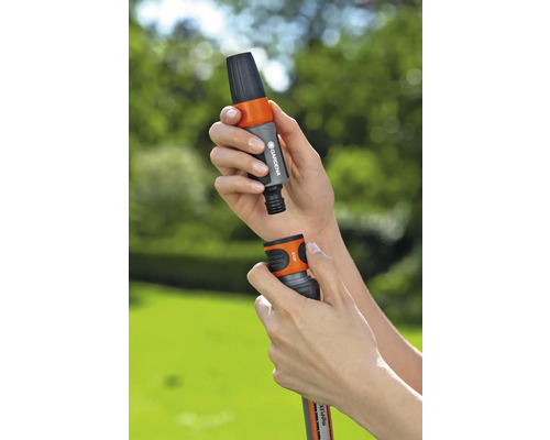 Osoba připojuje spojku zahradní hadice